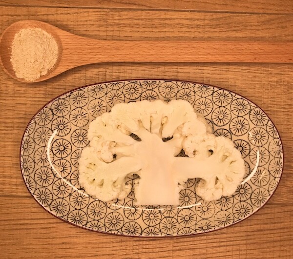 Cavolfiore su piatto ovale accompagnato da lievito secco su cucchiaio in legno